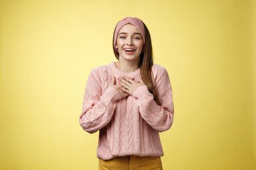 Grateful delighted charming young 20s woman wearing sweater pressing arms to chest happily, thankful, expressing gratitude, heartfelt appreciating gesture smiling amused, in love with romantic gift