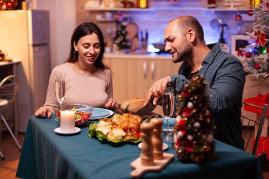 Married happy couple sitting at dining table in xmas decorated kitchen