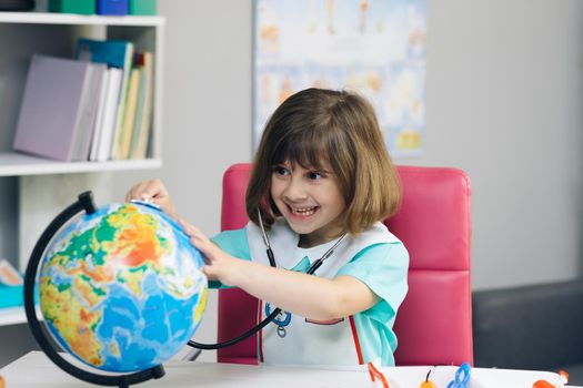 Ecology and global warming concept. Earth Temperature with Thermometer Icon for Global Warming and Climate Change. Little kid girl dressed in a doctor's suit measures the temperature of the Earth