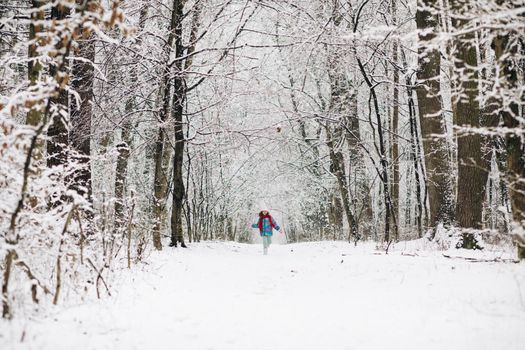 Child girl are having a fun running between snow trees in winter time, happiness concept. Happy girl running on snow in winter
