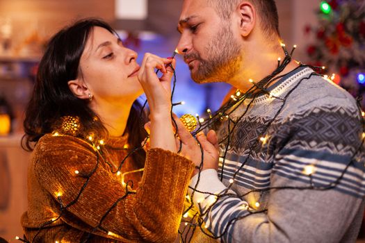 Happy amused couple stucking in christmas tree lights
