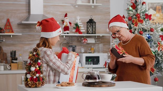 Happy family wearing santa hat surprising each other with wrapper xmas present gift