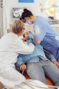 Senior woman technician checking teeth examining sick patient