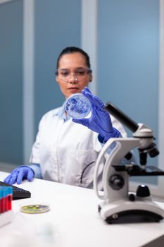 Scientist woman analyzing petri dish with microorganism bacteria