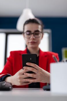 Selective focus detail on smartphone while businesswoman is texting
