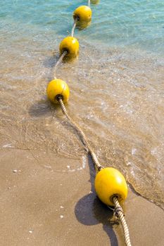 Floating buoy and rope dividing the area on the beach