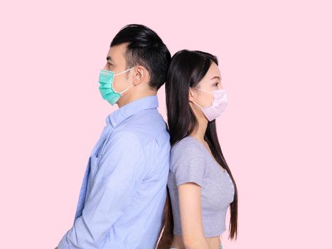 Young couple wearing medical mask and standing back to back