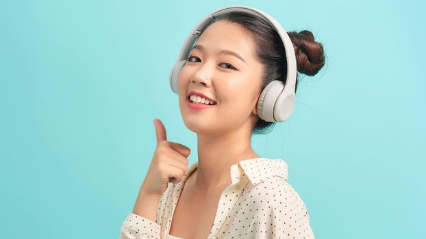 Teenager girl isolated on blue background listening music