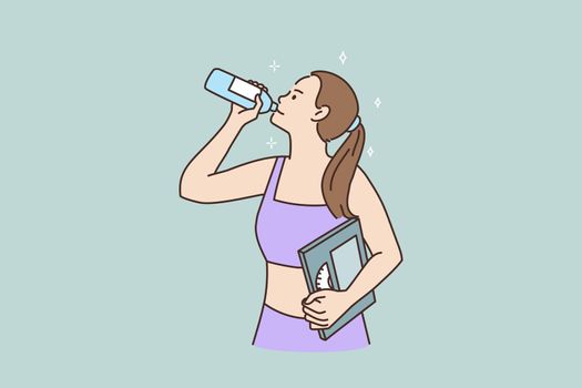 Toned sporty woman with weight scales drink water
