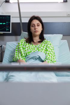 Sick woman wearing with nasal oxygen tube looking into camera resting in bed
