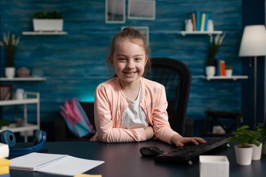 Portrait of little primary school kid sitting at home desk