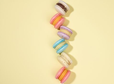 baked macarons with different flavors on a beige background, top view