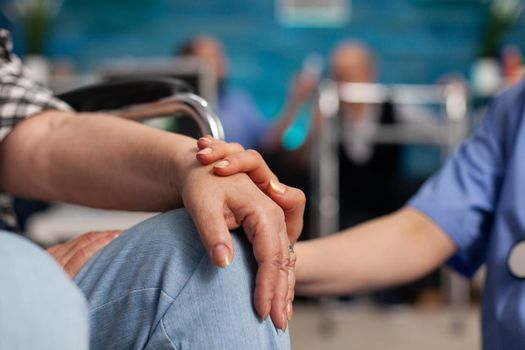 Social assistant worker consoling handicapped pensioner patient touching hands