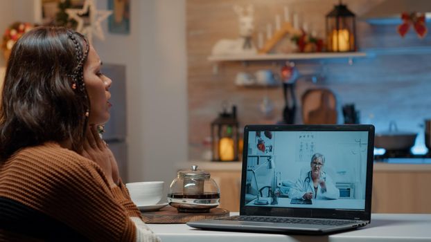 Woman with flu using telemedicine on laptop at home