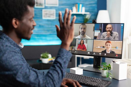 Black man waving to colleagues on video call chat