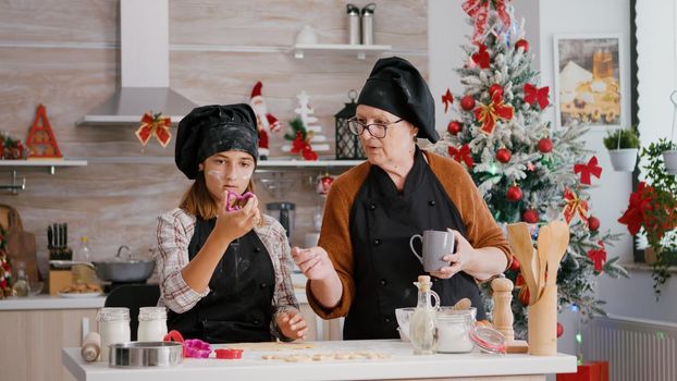 Grandma explaining to grandchild how to make traditional xmas homemade gingerbread dessert