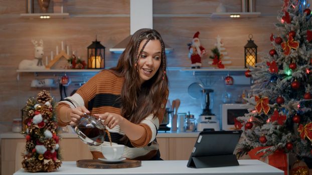 Woman pouring coffee while chatting on video call
