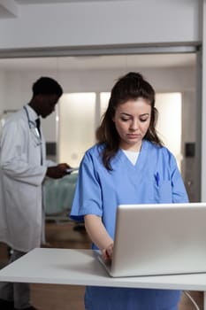 Caucasian woman using laptop at desk in hospital ward