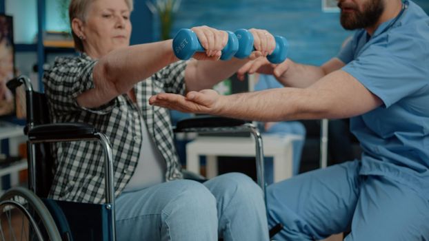 Close up of disabled woman using dumbbells for recovery