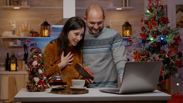 Cheerful couple receiving presents on video call for christmas