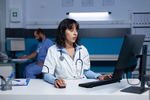 Medical specialist using computer and keyboard at night