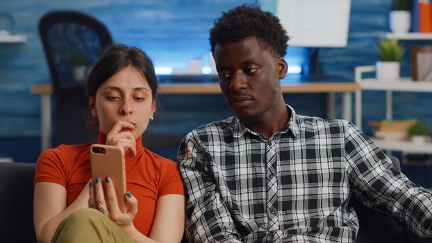 Married interracial couple using smartphone at home
