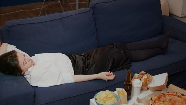 Young person falling asleep on couch dropping TV remote