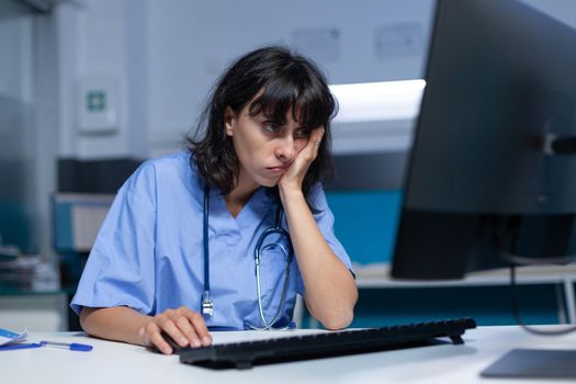 Medical specialist falling asleep at desk and using computer