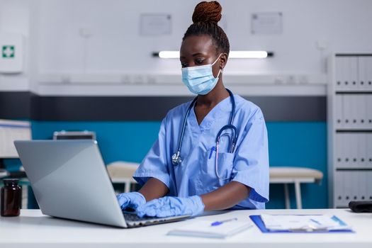 Black woman with nurse profession using modern laptop