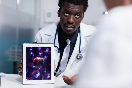 Doctor of african american ethnicity holding digital tablet