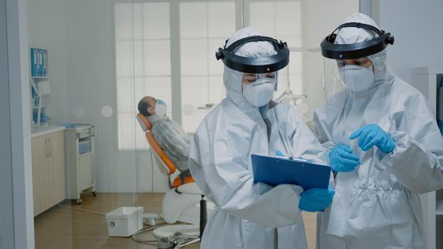 Professional stomatologists wearing ppe suits at oral clinic