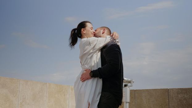 Young couple kissing on top of skyline tower above town