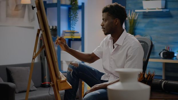 Adult of african american ethnicity drawing vase on canvas