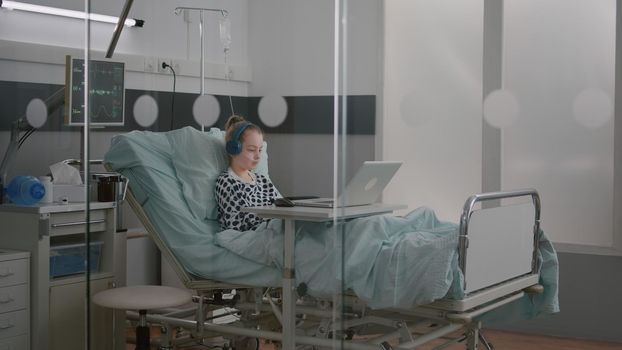 Alone sick girl patient with oxygen nasal tube relaxing in bed wearing headphones