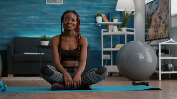 Portrait of black athlete sitting in lotus position on floor enjoying morning workout