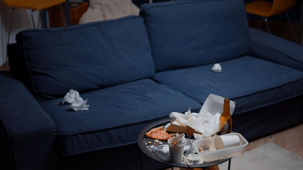 Chaos in empty living room with food garbage on table