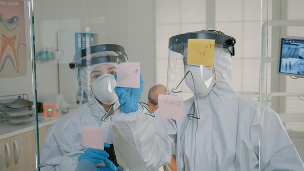 Orthodontists in ppe suits making diagram with sticky notes