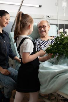 Cheerful granddaughter bringing flowers to elderly grandparent