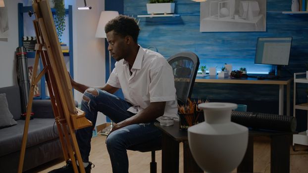 African american adult making fine art sitting in artwork studio