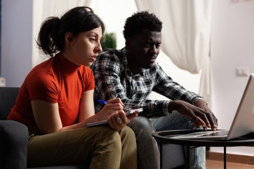Interracial couple calculating tax money using laptop