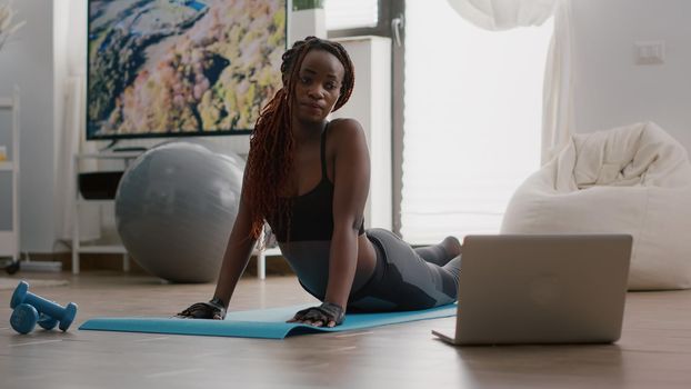 Flexible black woman practicing sport during yoga morning workout