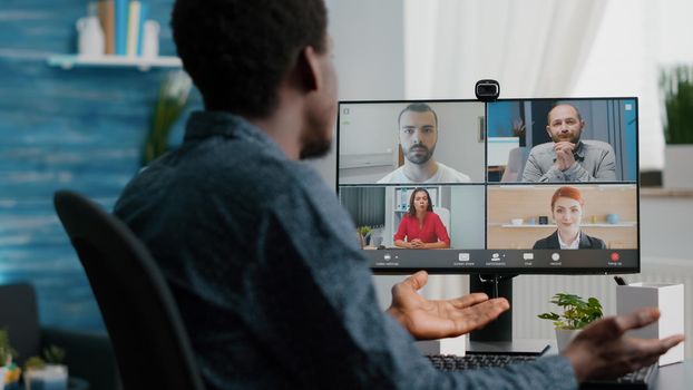 Close up of african american man on online conference video call with his colleagues. Computer user working from home in home office chatting using internet distance communication