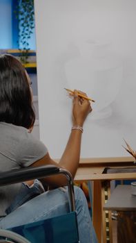 Black invalid artist with handicap using pencil on canvas