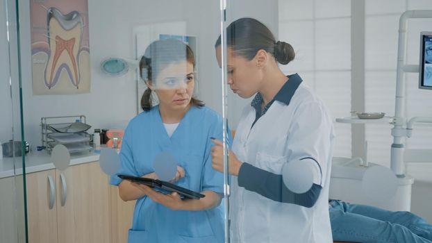 Dentist and assistant analyzing modern tablet screen