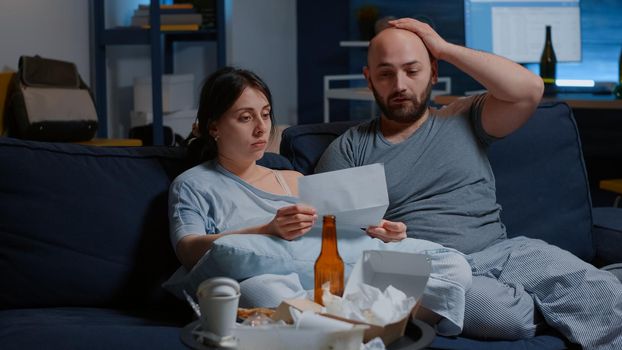 Young stressed married couple starting to cry reading bad news