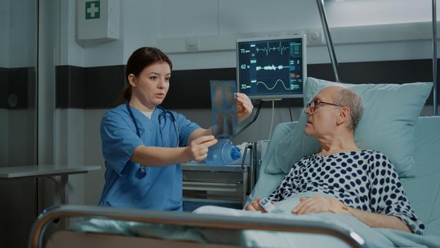 Nurse explaining xray test results to patient in hospital ward