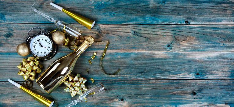 Overhead view of Happy New Year with gold decorations plus champagne bottle and glasses on blue faded wood 