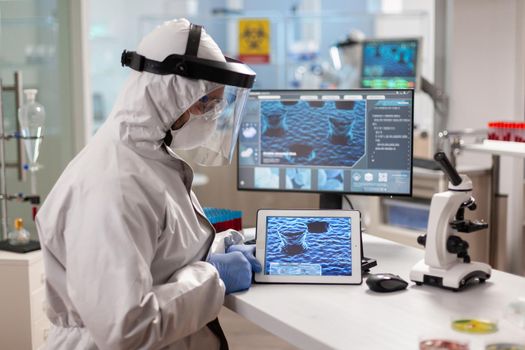 Laboratory chemist wearing ppe suit using tablet pc