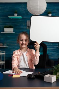 Portrait of smiling little schoolchild holding white board looking into camera