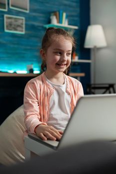 Clever smiling schoolkid working at literature homework browsing educational information
